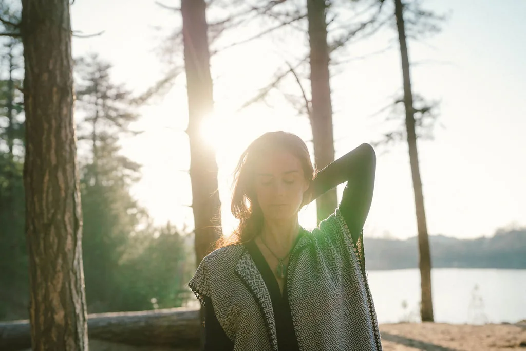 Dany Fenton looking directly at camera, placing a patterned black-and-white shawl over her head in warm golden light – a direct, present invitation to connect