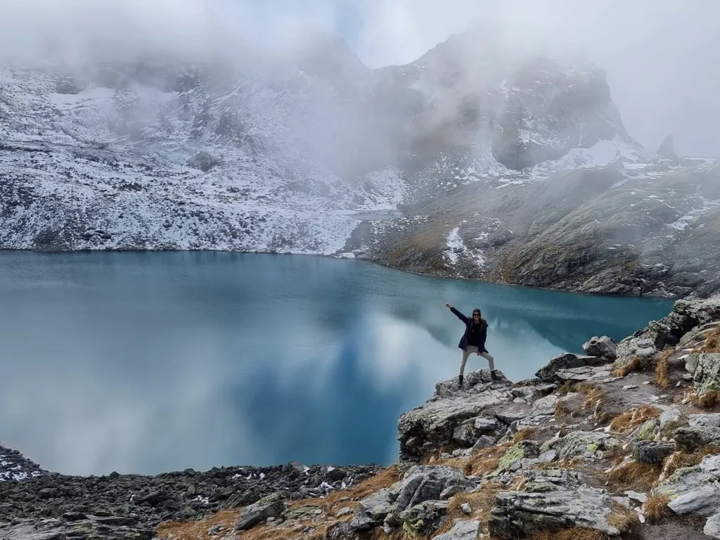 Dramatic alpine mountain lake surrounded by snow and clouds, representing the stillness and depth of winter