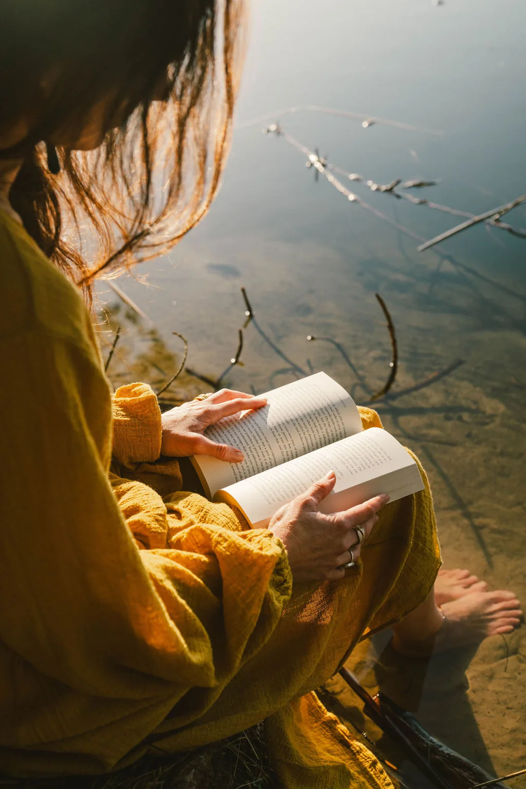 Close-up of Dany Fenton reading quietly by a sunlit lake, golden light on her face